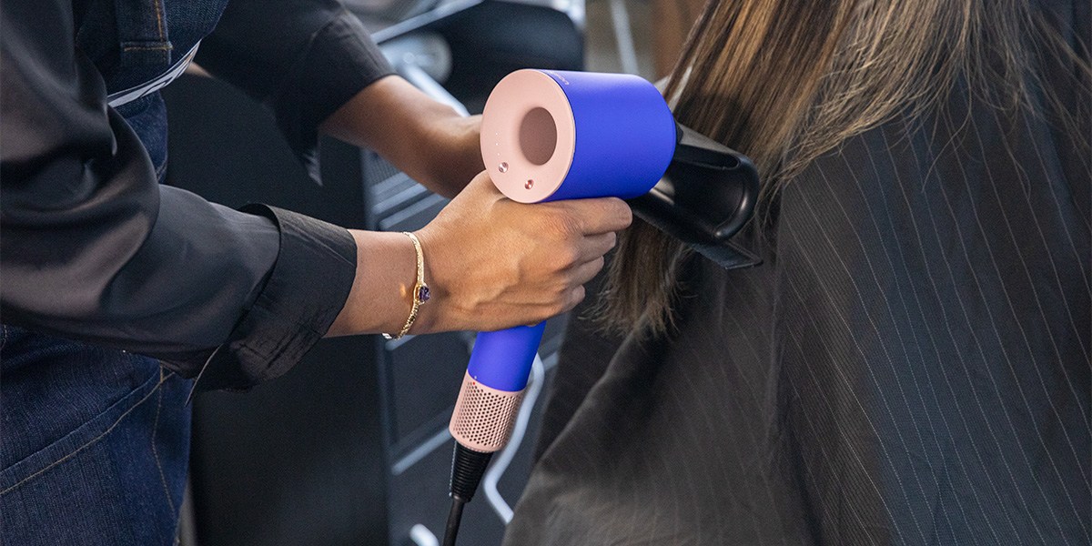 Stylist using Dyson Supersonic Hair Dryer's attachments to dry hair